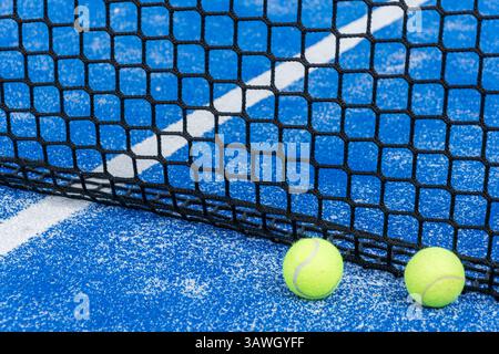 Padel-Bälle am Netz bereit für das Spiel auf dem blauen Platz, Padel-Szene Nahaufnahme der Bälle und Netz auf Blau Stockfoto