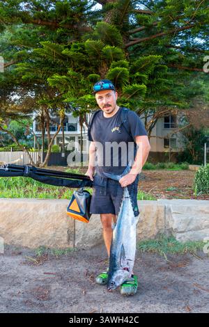 Ein Fischer steht mit einem Südlichen Blautunfisch (Thunnus maccoyii), frisch gefangen am Avoca Beach New South Wales, Australien Stockfoto