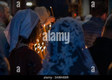 Eine Frau hält während der Osterwache im Kloster St. Michaels mit goldener Kuppel in Kiew im April 2025 Kerzen. Ihr Gesicht wird von Kerzenlicht beleuchtet Stockfoto
