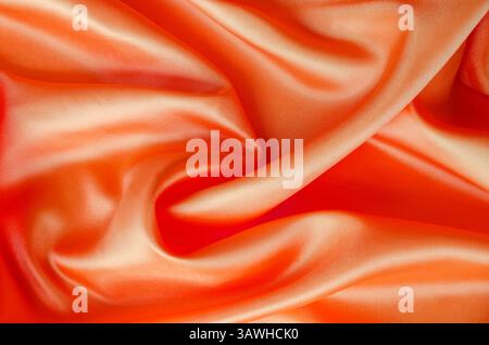 Leuchtendes Satin-Material in hellroter Farbe, das fließende Bewegungen und Glanz bietet. Geeignet für Design und Hintergrundtapeten. Stockfoto