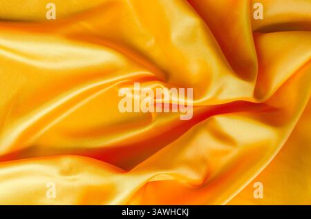 Makroaufnahme aus goldenem Seidentuch mit sanften Falten und poliertem Satin-Finish Stockfoto