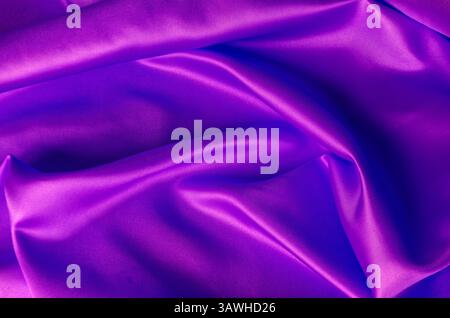 Draufsicht auf glänzendes, kastanienbraunes Satin-Tuch mit strahlenden Oberflächentexturen und feiner gewebter Textur in natürlichen Falten. Stockfoto