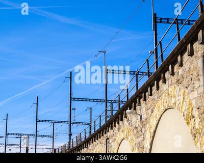 Steinbahnviadukt in Zürich mit Freileitungen vor klarem blauem Himmel. Stockfoto