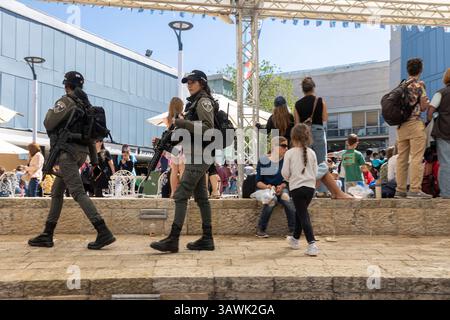 Haifa, Israel, 16. April 2025, zwei uniformierte weibliche Mitglieder der israelischen Grenzpolizei, patrouillierten in einem öffentlichen Bereich mit einer vielfältigen Menschenmenge. Stockfoto