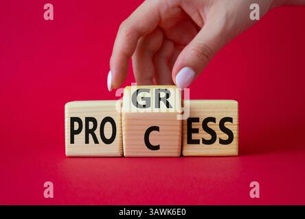 Symbol für Prozess und Fortschritt. Die Hand des Geschäftsmannes dreht Holzwürfel und ändert das Wort Prozess und Fortschritt. Schöner roter Hintergrund. Business und Profi Stockfoto