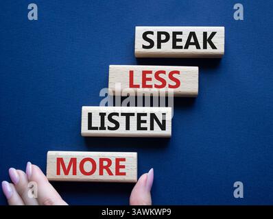 Weniger sagen, mehr hören. Holzblöcke mit Wörtern sprechen weniger Hören Sie mehr. Wunderschöner tiefblauer Hintergrund. Geschäftsmann Hand. Geschäftlich und sprechen Sie l Stockfoto