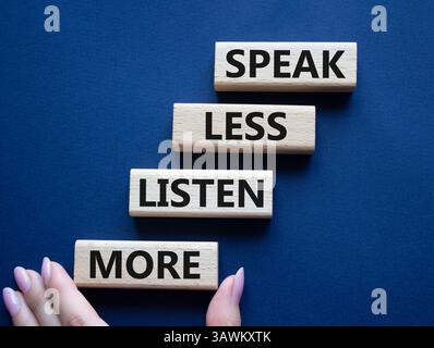 Weniger sagen, mehr hören. Holzblöcke mit Wörtern sprechen weniger Hören Sie mehr. Wunderschöner tiefblauer Hintergrund. Geschäftsmann Hand. Geschäftlich und sprechen Sie l Stockfoto