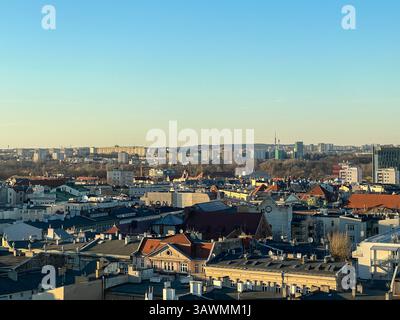 Panoramablick auf die Stadt mit traditionellen europäischen Dächern im Vordergrund und modernen Wohnblöcken in der Ferne, erfasst während der goldenen Stunde Stockfoto
