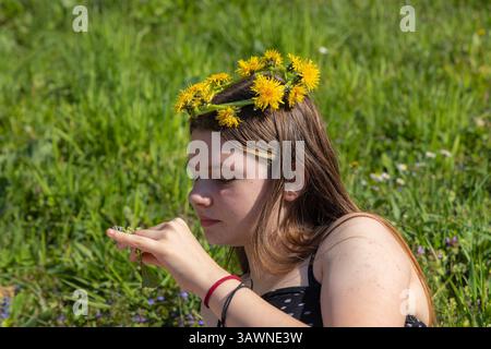 Ein weibliches Kind mit einer Löwenzahngirlande auf dem Kopf Stockfoto