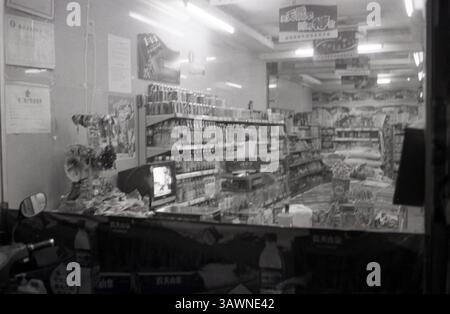 In einem belebten Eckgeschäft in der Nacht mit Regalen gefüllt mit Snacks und Getränken beleuchtet von hellen Leuchtstofflampen : Convenience Store Interior aus Motorrad, 2010er Jahre, China Stockfoto