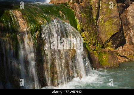 Nahaufnahme des Wasserfalls mit algenbedeckten Felsen am Dream Lake im Chinesischen Garten im Herbst, Montreal Botanical Garden, Quebec, Kanada. Stockfoto