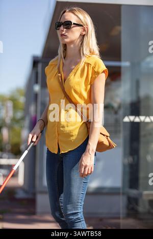 Blinde Frau, die auf dem Bürgersteig läuft Stockfoto