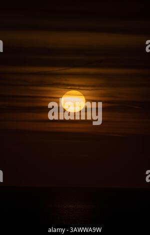 Nahaufnahme des Sonnenuntergangs über dem Meer in Grottammare, Italien. Dünne Wolken ziehen sich vor der Tür vorbei und schaffen einen stimmungsvollen und warmen Blick auf das Meer. Stockfoto