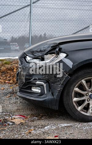 Beschädigtes schwarzes Auto mit zerdrückter Front nach einem Unfall Stockfoto