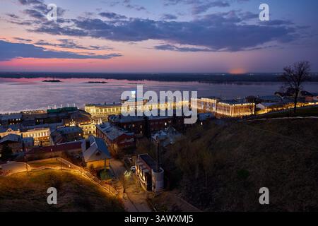 Ein ruhiger Abend über dem Wolga-Fluss in Nischni Nowgorod, bei dem sich die beleuchtete Wolga Reederei unter einem pastellfarbenen Himmel auf dem Wasser reflektiert Stockfoto
