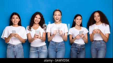 Fünf Multirassische Frauen Mit Smartphones Über Blue Studio Hintergrund, Panorama Stockfoto