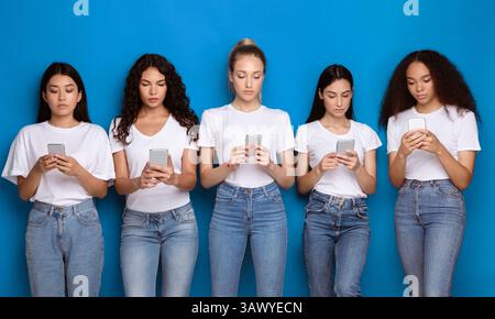 Fünf Verschiedene Millennial Frauen Mit Handys Stehen Über Blauem Hintergrund Stockfoto