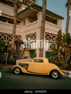 Ein gelber Oldtimer steht vor einem Palmengebäude in San Clemente, Orange County, Kalifornien Stockfoto