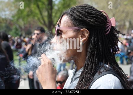 Eine junge Frau raucht einen Joint während der Feier 420 im Washington Square Park in New York, New York, am Sonntag, den 20. April 2025. Die Menschen auf der ganzen Welt feiern ihr Lieblings-schlechtes Vergnügen: Marihuana. (Foto: Gordon Donovan) Stockfoto
