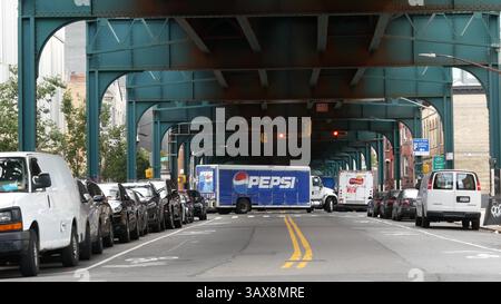 New York City, USA - 31. August 2023: Pepsi Truck, erhöhte U-Bahn über der Straße. Metropolitan Bridge über die Straße, Queens. Long Island U-Bahn-Linie. Autos unter metallischen Bahngleisen. New York City Life. Stockfoto