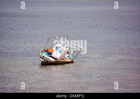Das alte, geneigte Fischerboot tauchte teilweise in flaches Wasser im Vourkari Wetland ein und schuf eine Szene des Verfalls und der ruhigen Einsamkeit. Stockfoto