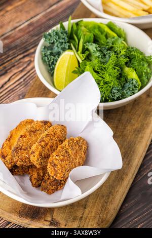 Knusprige Hähnchenflügel mit Gemüse und Pommes frites auf Holztisch Stockfoto