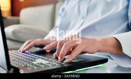 Nahaufnahme weiblicher Hände mit Laptop-Computer, Tippen auf der Tastatur, während Sie auf dem Sofa sitzen, Programmierer, Solopreneur, Fernarbeit, Arbeit von zu Hause aus, freiberuflich Stockfoto
