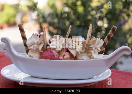 Köstlicher Eisbecher mit Fruchteis, Schlagsahne und Eiskegel Stockfoto