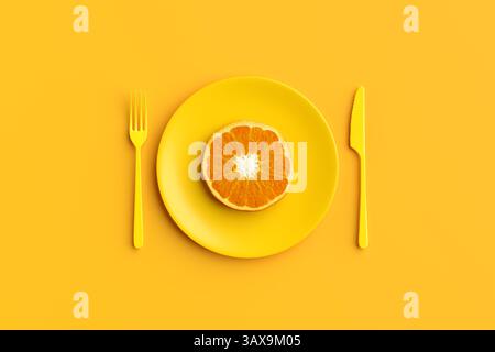 Lebendiges Stillleben mit einer orangefarbenen Scheibe auf einer gelben Platte mit passender Gabel und Messer für eine einfarbige Lebensmittelkomposition. 3D-Rendering. Stockfoto