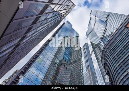 Hohe reflektierende Bürotürme mit Glasfassaden, die von der Straßenebene erfasst wurden und nach oben schauen Stockfoto