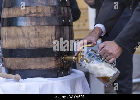 Bierfässer aus Holz anzapfen und den ersten Bierbecher füllen - Nahaufnahme Stockfoto