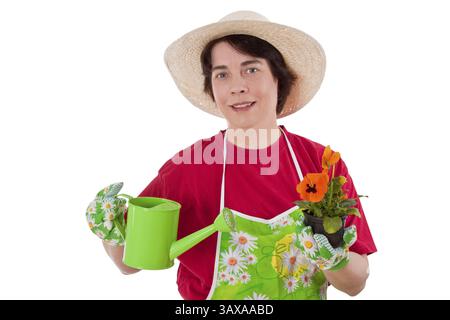 Frau mit Gärtnerschürze und Strohhut, die Pflanzen und Gießkanne hält Stockfoto
