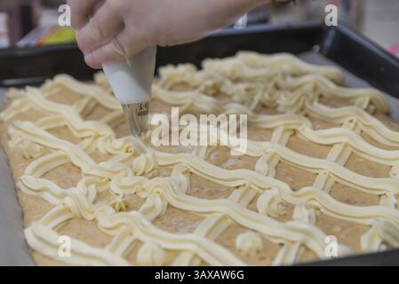 Konditor dekoriert Cremeschneiden in der Bäckerei mit einem Gebäckbeutel - Nahaufnahme Stockfoto