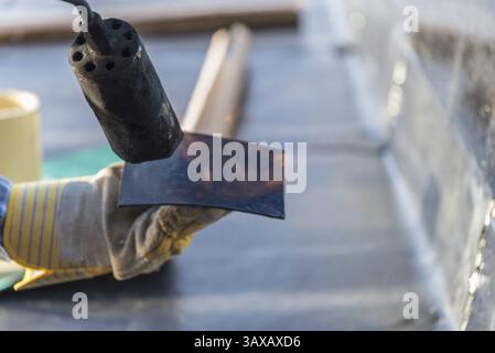 Bauarbeiter auf der Baustelle mit Gasabdichtungen mit Abschirmfilz auf dem Dach - Nahabschirmung Stockfoto
