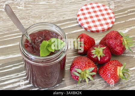 Hausgemachte Erdbeermarmelade in einem Glas mit Minzblättern hausgemachte Erdbeermarmelade in einem Glas mit Minzblättern Stockfoto