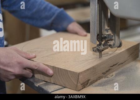 Zimmermann schneidet ein Stück Holz mit einer Tischbandsäge - Nahaufnahme Stockfoto