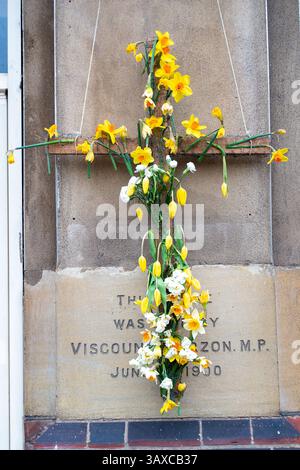 Slough, Großbritannien. April 2025. Ein Kruzifix mit Narzissen und Tulpen vor einer Kirche in Slough, Berkshire nach Gottesdiensten am Ostersonntag. Heute wurde bekannt gegeben, dass Papst Franziskus leider verstorben ist. Quelle: Maureen McLean/Alamy Live News Stockfoto