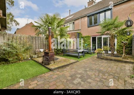 Eine ruhige Gartenszene mit üppigem Grün, einem gemütlichen Sitzbereich und Dekorationselementen im Freien, perfekt für Entspannung und Outdoor-Genuss. Stockfoto