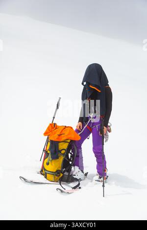 Skilangläufer stehen im Schnee mit Jacke auf dem Kopf gegen die Sonne Stockfoto