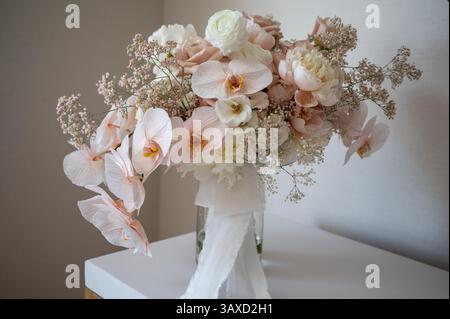 Blush und Elfenbein Orchideenstrauß mit Band in Glasvase Stockfoto