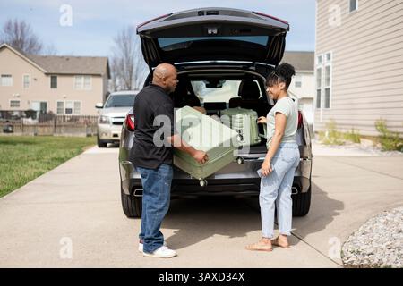 Ein Mann, der der Frau hilft, Koffer im Auto zu packen Stockfoto