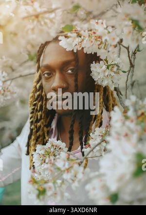 Ein schwarzer Mann mit Dreadlocks in einem Kirschblütenbaum Stockfoto