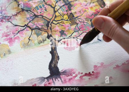 Die Hand eines Mannes hält einen beladenen Pinsel und malte einen Kirschblütenbaum mit Aquarellfarbe, UK. Konzept: Hobbys für Erwachsene, Hobbys für Erwachsene, Künstler Stockfoto