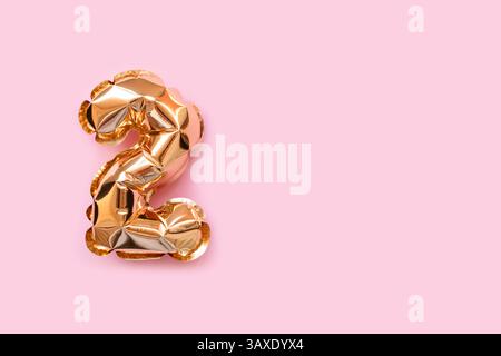 Nummer zwei goldene Ballons auf rosafarbenem Hintergrund. Platz für Text. Stockfoto
