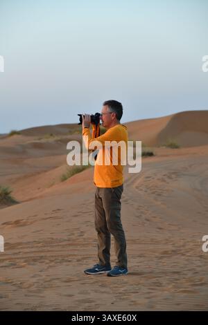 Touristen machen Fotos in der Wüste Rub Al Khali, Sultanat von Oman. Wahiba Sands Dünen bei Sonnenuntergang, Arabische Halbinsel Stockfoto