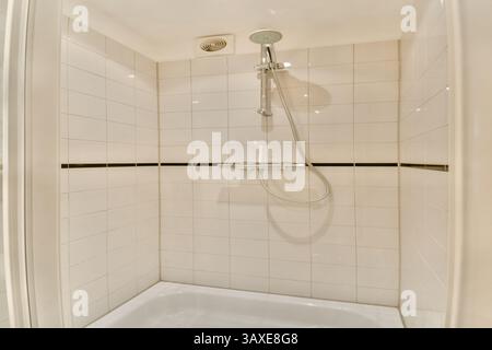 Eine elegante und moderne Duschkabine mit weiß gefliesten Wänden, minimalistischem Design und modernem Duschkopf für ein gehobenes Badeerlebnis. Stockfoto