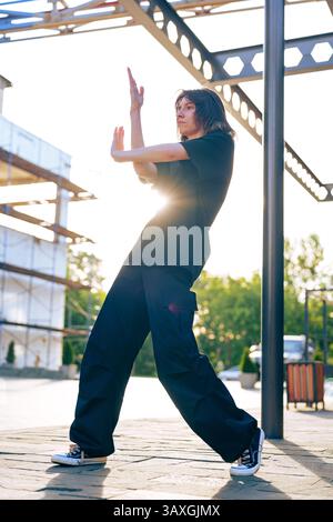 Stadttänzer, die am späten Nachmittag auf einer sonnendurchfluteten Baustelle eine energiegeladene Routine vorführt Stockfoto