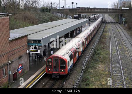 Am 20. Februar 2025 führt DM91125 von 92 Stock einen Zug nach Osten nach Epping in den Bahnhof Hanger Lane, während in der Ferne ein Zug nach Westen fährt. Stockfoto