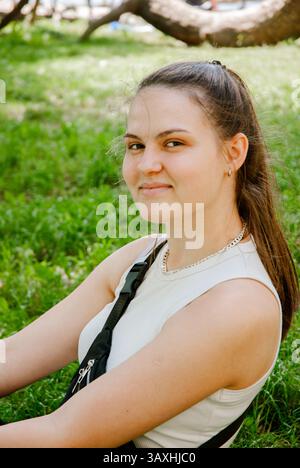 Entspanntes Outdoor-Porträt einer lächelnden jungen Frau in lässiger Sommerkleidung. Wochenendkonzept in der Nähe des Waldes und Sees. Stockfoto