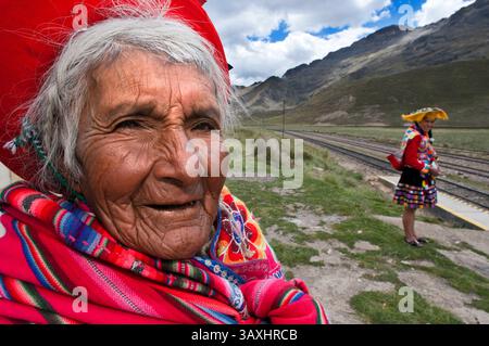 Oktober 2016 - Peru - Anden Explorer, Luxuszug von Cusco nach Puno. Eine alte Frau in traditioneller Kleidung in La Raya, die mit dem höchsten Punkt des Weges, 4313 Meter, zusammenfällt. Der Anden-Explorer-Zug Orient Express fährt zwischen Cuzco und Puno. Altiplano ist ein Hochplateau, das sich über den südlichen Anden erhebt, dem längsten Gebirgszug der Welt. Es handelt sich um eine mit Sedimenten gefüllte Vertiefung zwischen den östlichen und westlichen Ketten der Anden. Diese Füllung ereignete sich vor Millionen von Jahren, als ein alter Meeresboden hochgeschoben wurde, als die modernen Gipfel angehoben wurden. Erosionsbedingte Ablagerung Co Stockfoto